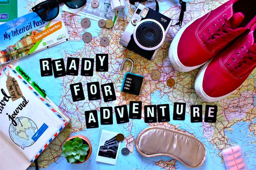 A creative collage of travel-related items including a map, camera, EuroRail pass, walking shoes, and so on.