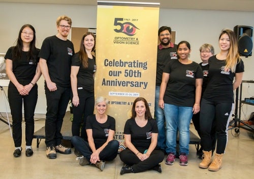 Optometry volunteers celebrate with the School's 50th Anniversary banner.