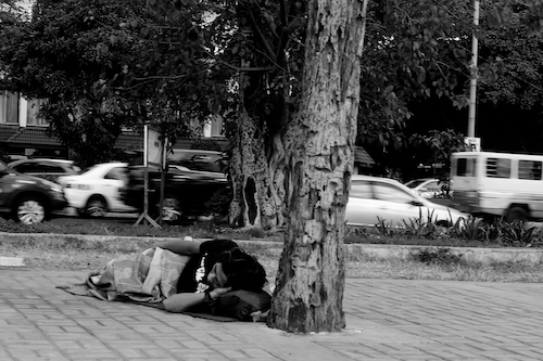 A person sleeps on a sidewalk.