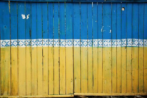 A wooden fence painted to look like the yellow and blue Ukrainian flag.