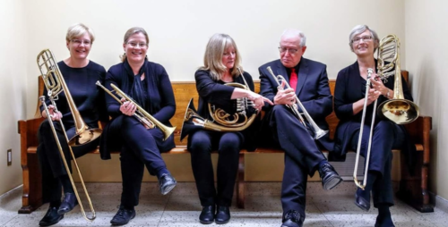 The five members of the Full House Brass sit with their instruments on a church pew.