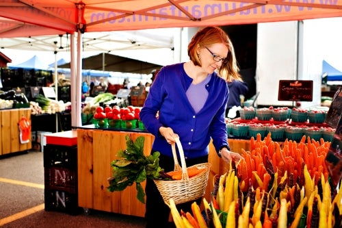 A woman browses for carrots at a farmer's market.