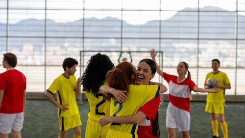 A stock photo of indoor soccer athletes hugging and celebrating.