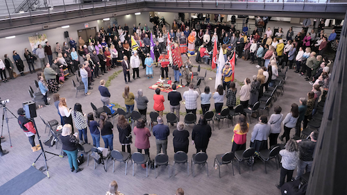 People stand in a circle in Federation Hall as the Eagle Staff ceremony takes place.