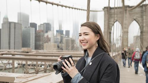 A woman takes photographs on a bridge.