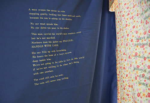 An art installation with a poem stitched into blue fabric.