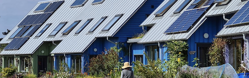 Townhomes with sloping roofs affixed with solar panels.