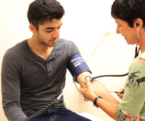 A doctor tests a man's blood pressure with a cuff.