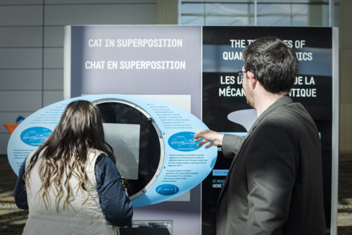 A &quot;Cat in Superposition&quot; pop-up booth with two people looking at it.