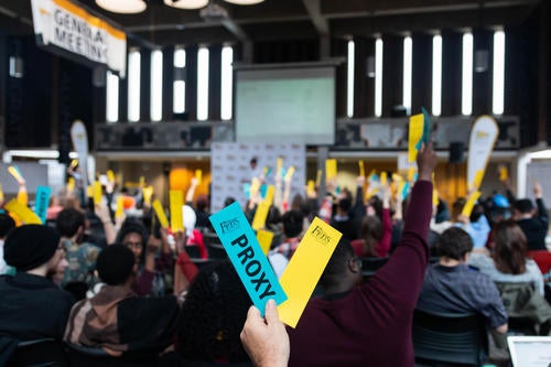 Voters hold up voting cards in the Student Life Centre Great Hall.