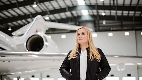Dr. Suzanne Kearns stands in an airplane hangar next to an aircraft.