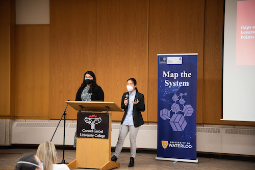Students pitch on stage at the Map the System campus finals event held at Conrad Grebel.