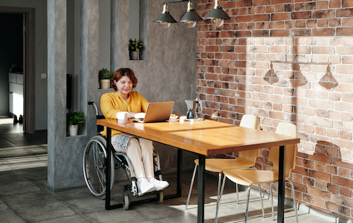 A woman in a wheelchair works at a table.