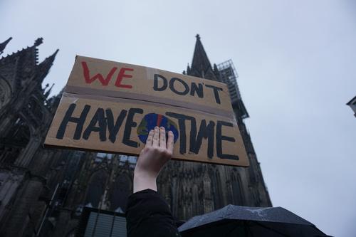 A person holds up a sign saying &quot;We Don't Have Time&quot;