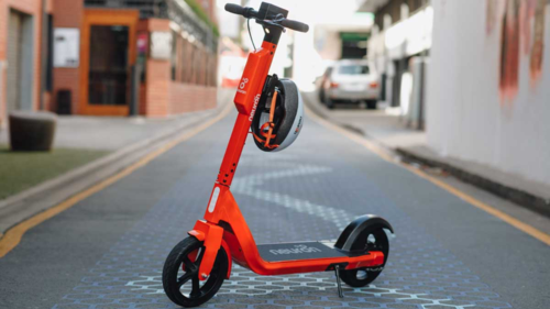 An orange Neuron e-scooter parked on a city street.