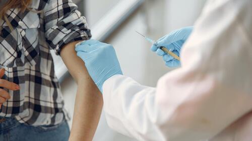 A healthcare worker prepares to deliver a vaccine shot to a patient.