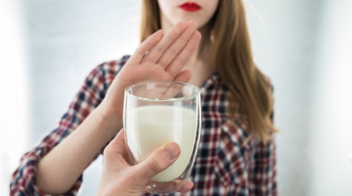 A woman puts up her hand to refuse a glass of milk.