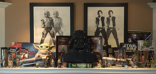 Star Wars collectibles and memorabilia arranged on a mantlepiece.