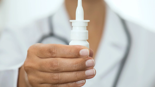 A person holds up a nasal spray bottle.