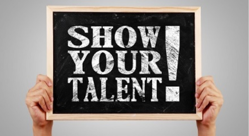 A person holds up a slate with &quot;Show Your Talent&quot; written on it.