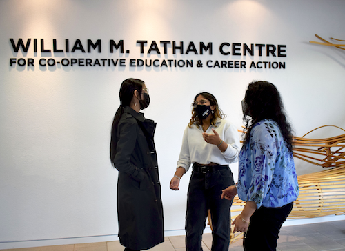 Students stand in the lobby of the Tatham Centre.