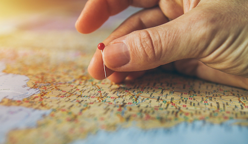 A hand puts a pin in a map.