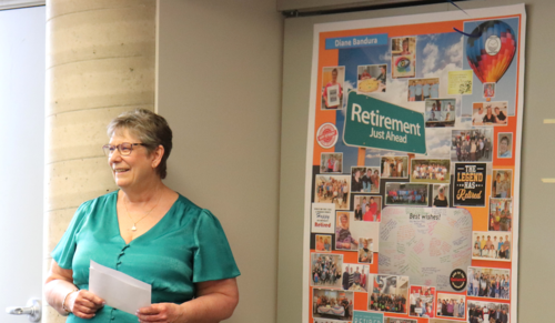 Diane Bandura stands next to a poster made for her retirement celebration.