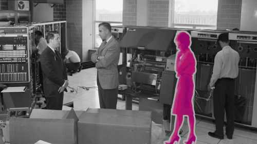 Marian Forster is shown in pink in an otherwise black and white photo of a computer room at Waterloo, with several of her co-workers.