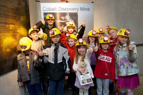 Kids with hard hats and helmet lights pose in the Earth Sciences Museum.