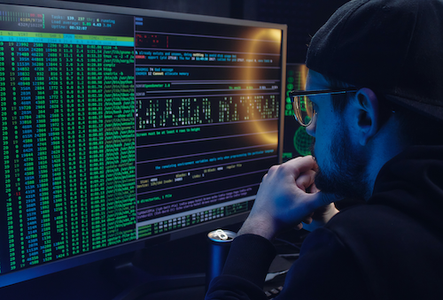 A computer hacker stares intently at a screen.