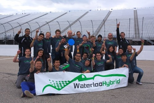 Members of the Waterloo Formula Hybrid team celebrate with their banner.