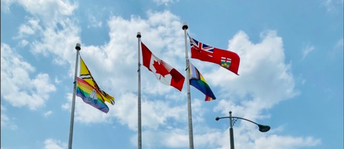 Two Pride flags fly adjacent to the Canadian, Ontario, and University of Waterloo flags.
