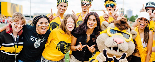 People wearing University of Waterloo clothing cheer on a sports team with King Warrior.