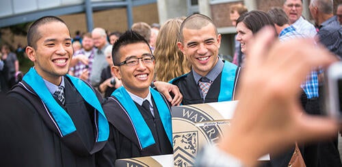 Three graduates smiling at a camera