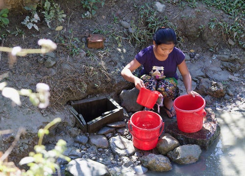 A woman pours water into buckets.