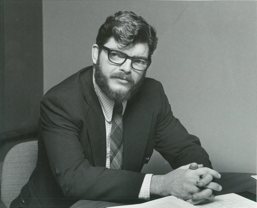 Dr. Gordon Nelson sits at a table in 1975.