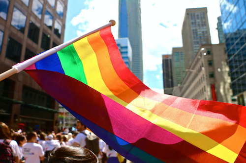 The rainbow Pride flag being flown at a parade.