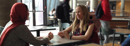 Professor Hilary Bergsieker sits with a woman in a food court.