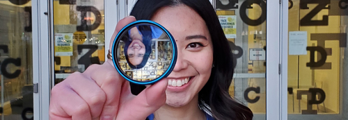 A woman smiles as she looks through a lens.