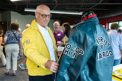 An alumnus checks out a vintage University of Waterloo leather jacket while wearing a vintage Waterloo jacket himself.
