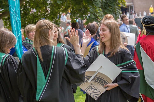 Faculty of Environment graduates high five one another after convocation.