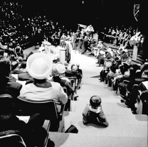 A child sits in the aisle of the Theatre of the Arts while the convocation ceremony plays out on stage.