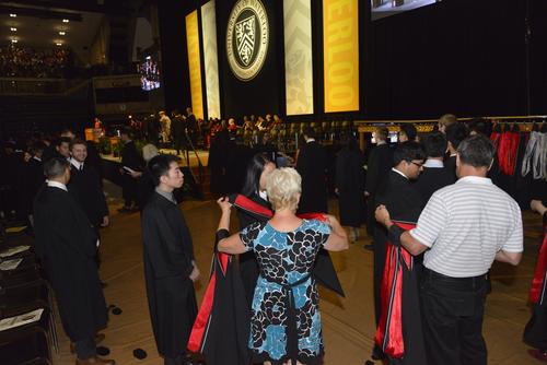 Volunteers hand out hoods to waiting students as they prepare to cross the stage at Convocation.
