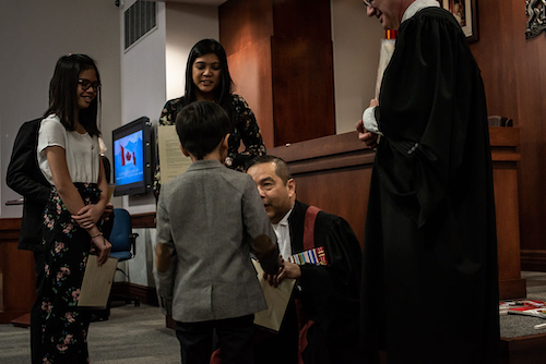 Judge Albert Wong greets a child during a citizenship ceremony.