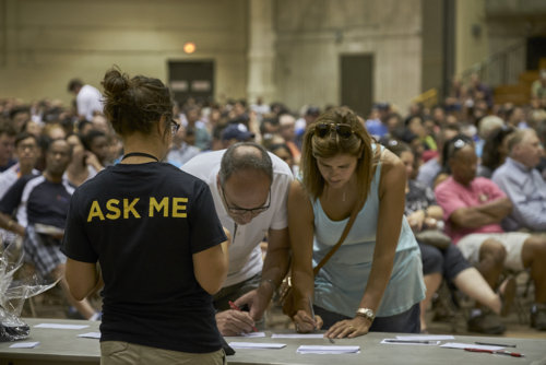 People sign up at a table at the Waterloo Ready event while a volunteer sports an &quot;ask me&quot; shirt.