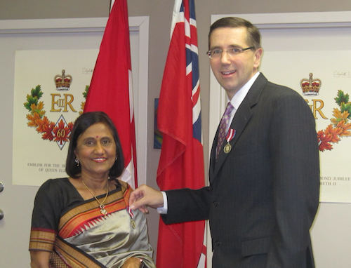 Chandrika Anjaria receives the Order of Canada medal from MPP John Milloy in 2013.
