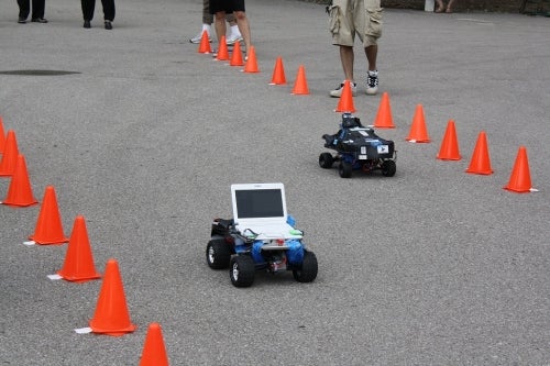 Two robotic racecars race on a track.