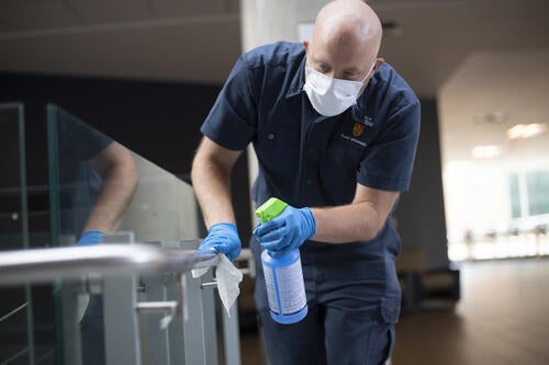 A member of the Plant Operations team disinfects high-touch surfaces in the STC building.
