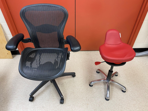 A traditional desk chair next to a Dynamic chair that looks more like a stool on wheels.