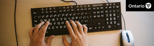 A person uses a computer keyboard that featured enlarged letters and numbers